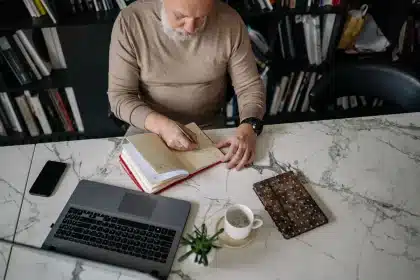 Homme tenant un journal de santé avec des légumes et une bouteille d'eau sur un bureau