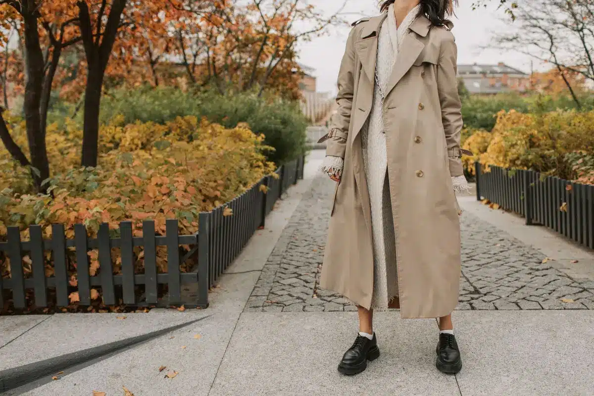 Femme portant des sneakers colorées sous un pardessus mi-long pour un style décontracté.