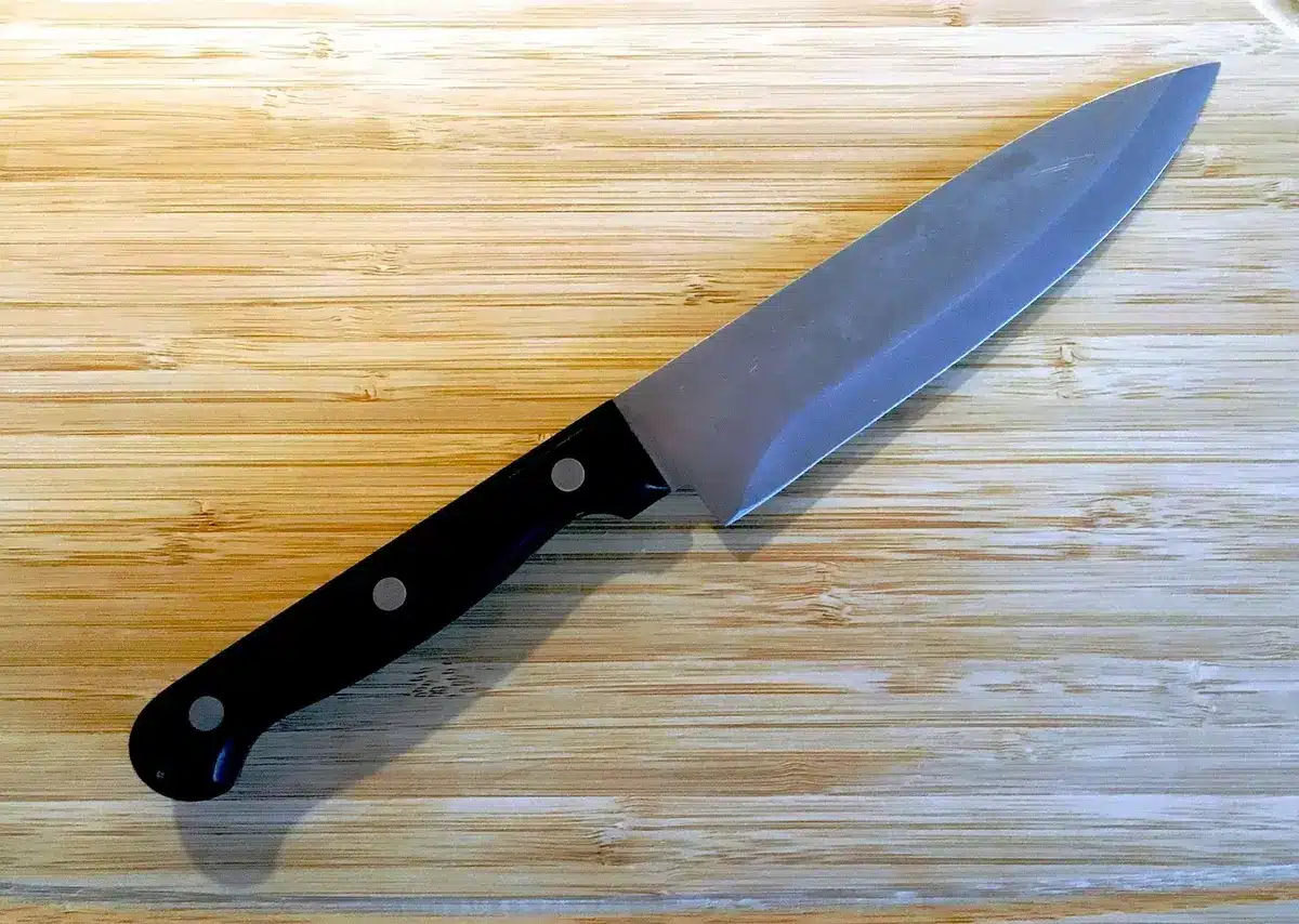 Tiges de rhubarbe fraîches découpées sur une planche à découper avec ustensiles de cuisine