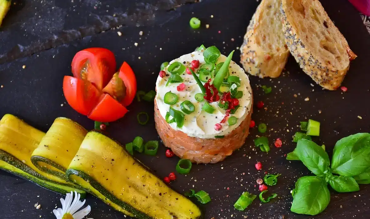 Tartare de poisson dressé en assiette avec betterave, asperges et zeste de citron vert