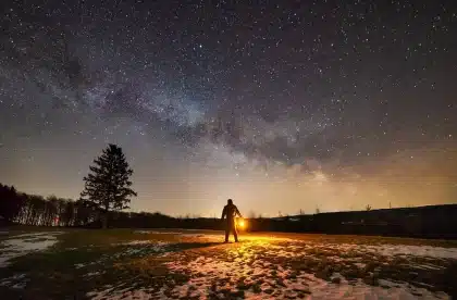 Personne assise dans un lit sombre, l'air préoccupée, cherchant à se rendormir la nuit