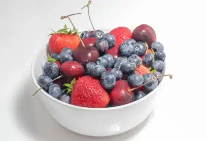 Bol de fraises mûres sur une table de cuisine éclairée par une grande fenêtre
