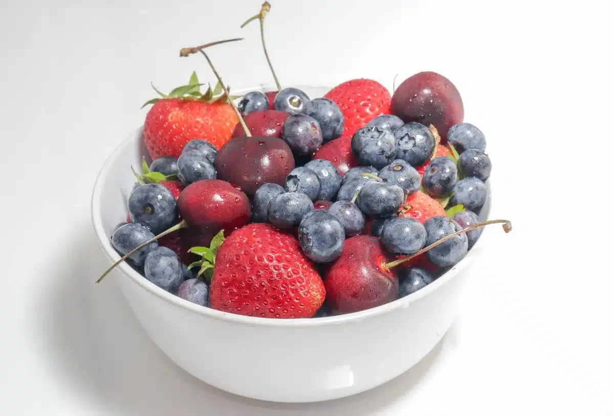 Bol de fraises mûres sur une table de cuisine éclairée par une grande fenêtre