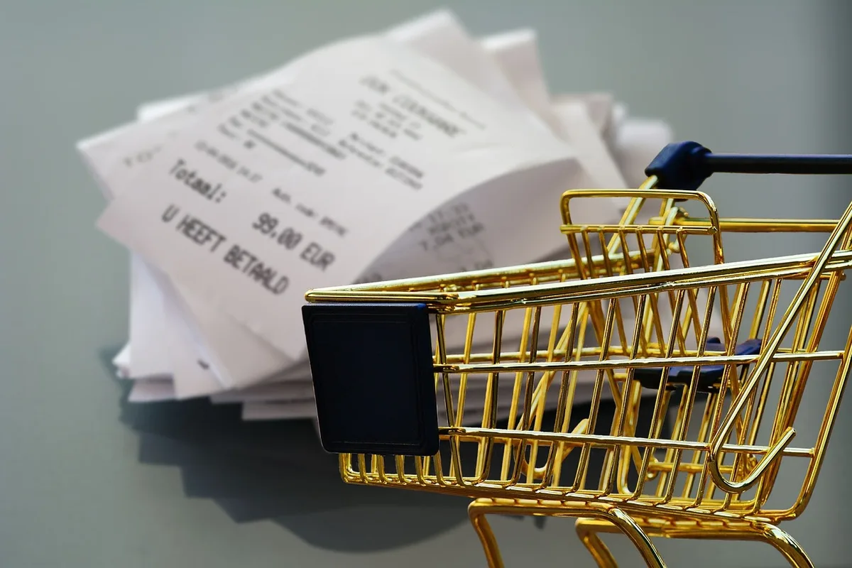 Mains triant des courses sur une table de cuisine en plein jour avec reçu et bocaux