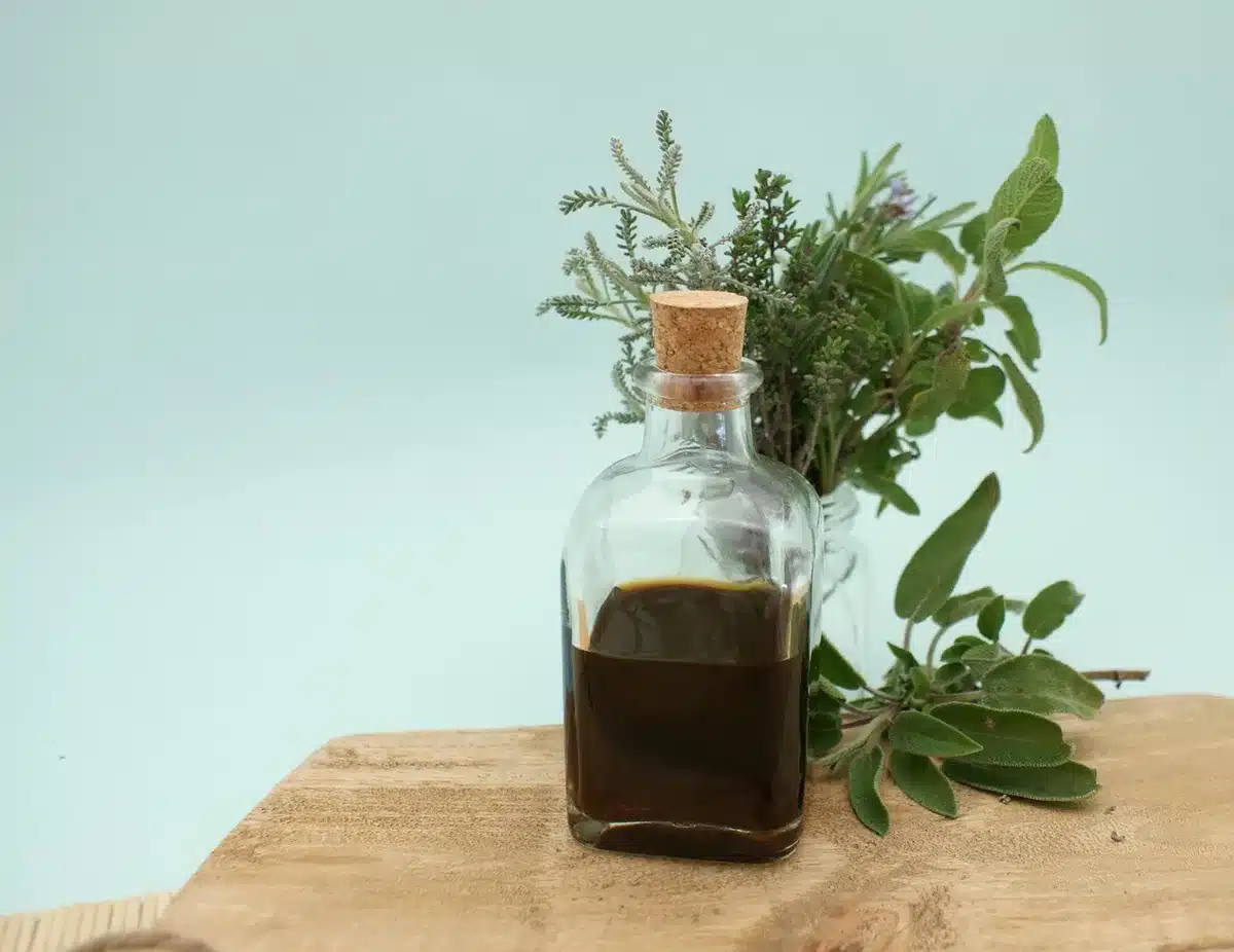 Bouteilles de compléments et plantes sèches (sauge, actée, huile d'onagre) posées sur une table