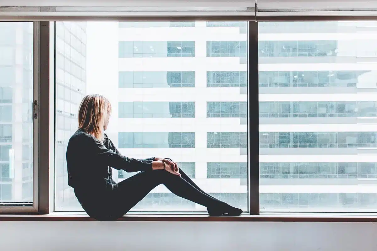Personne assise près d'une fenêtre en journée pratiquant une respiration apaisante